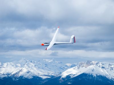 Segelflugzeug in der Luft vor verschneiten Bergen